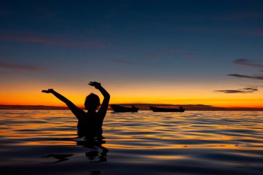 Rincon del Mar, Sucre, Kolombiya 'da çarpıcı bir günbatımında sakin sularda huzur içinde yüzen bir insan.