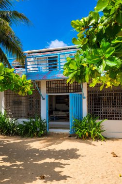 Rincon del Mar, Sucre, Kolombiya 'daki yemyeşil ve açık mavi gökyüzü ile çevrili canlı bir sahil evi.