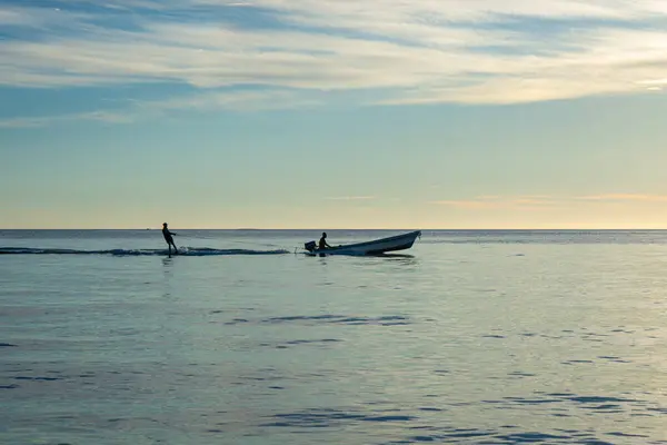 Günbatımında Rincon del Mar, Sucre, Kolombiya 'da su kayağı ve tekne gezisi sahnesi.