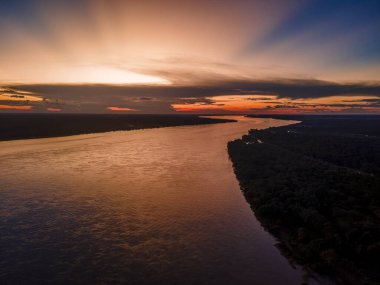 Leticia, Kolombiya 'da Amazon Nehri üzerinde sakin suları ve canlı gökyüzünü gösteren sakin bir günbatımı, doğa severler ve seyahat meraklıları için mükemmel..