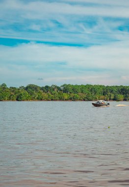 Amazon Nehri 'nin sakin sularında süzülen sakin bir tekne. Etrafı yemyeşil tropikal ormanlarla ve Amazonlar, Kolombiya' daki canlı biyolojik çeşitlilikle çevrili..