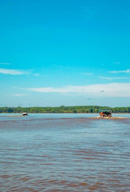 Kolombiya, Leticia 'daki Amazon Nehri' nin çamurlu sularında gezinen iki tekne, yemyeşil tropikal ormanlarla çevrili..