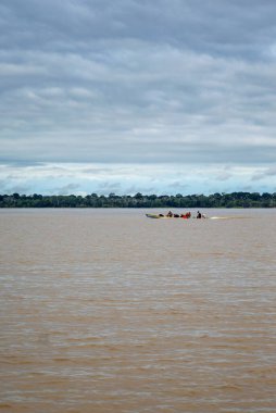 Amazon Nehri 'nin sakin manzarası. İnsanları taşıyan bir kano. Leticia, Amazonas, Kolombiya' da yemyeşil tropikal ormanlarla çevrili..