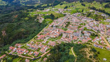 Guatavita 'nın çarpıcı hava manzarası, kırmızı çatıları ve gölün ve dağların manzaralı manzarası olan geleneksel beyaz binaları sergiliyor..