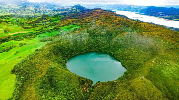 Guatavita 'nın çarpıcı hava manzarası, kırmızı çatıları ve gölün ve dağların manzaralı manzarası olan geleneksel beyaz binaları sergiliyor..