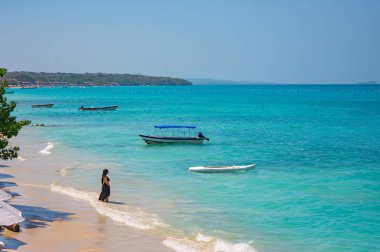 Playa Blanca, Cartagena, Kolombiya 'da el ele yürüyen bir çiftin romantik günbatımı sahnesi. Tatil ve turizm için mükemmel..