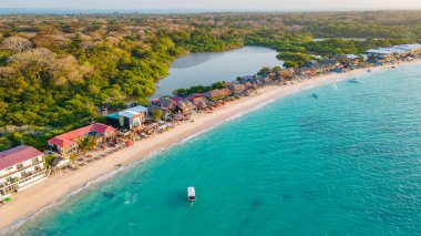 Playa Blanca, Cartagena, Kolombiya 'da el ele yürüyen bir çiftin romantik günbatımı sahnesi. Tatil ve turizm için mükemmel..