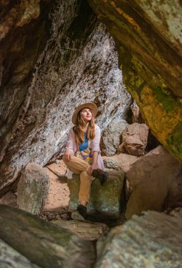Genç bir kadın, Guaviare, Kolombiya 'da bir mağarada manzaralı güzelliğin tadını çıkarıyor. Çarpıcı kaya oluşumları macerası için büyüleyici bir zemin oluşturur.
