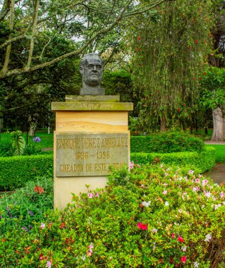 Bogot Botanik Bahçesi 'nde düzgünce budanmış çitlerle kaplı, bulutlu gökyüzünün altında canlı yeşillikler sergilenen sakin bir patika.