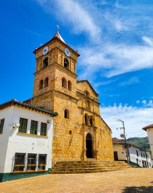Guadalupe, Santander, Kolombiya 'da bulunan ve mavi gökyüzüne karşı bir saat kulesinin yer aldığı tarihi bir kilisenin çarpıcı manzarası.