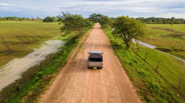 Kolombiya, Casanare 'deki yemyeşil manzaranın hava manzarası, dolambaçlı yollar ve bulutlu bir gökyüzünün altındaki açık alanlar.