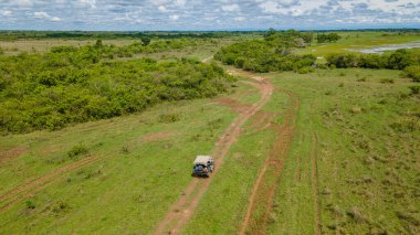 Kolombiya, Casanare 'deki yemyeşil manzaranın hava manzarası, dolambaçlı yollar ve bulutlu bir gökyüzünün altındaki açık alanlar.