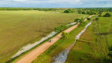 Kazanare, Kolombiya 'nın verimli arazisinde dolambaçlı bir toprak yolun havadan görünüşü canlı yeşil alanlar ve sakin doğal çevreyi gösteriyor..