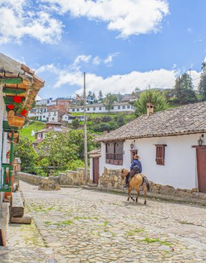 Mongui, Boyac 'ta bir at binicisi ve büyüleyici bir koloni mimarisinin yer aldığı kaldırım taşlı bir caddenin manzarası..