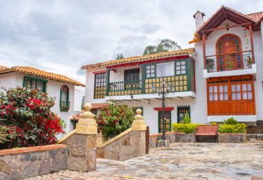 Pueblito Boyacense, Duitama, Boyac, Kolombiya 'da canlı çiçekler ve geleneksel mimari ile süslenmiş bir koloni caddesinin pitoresk bir görüntüsü..