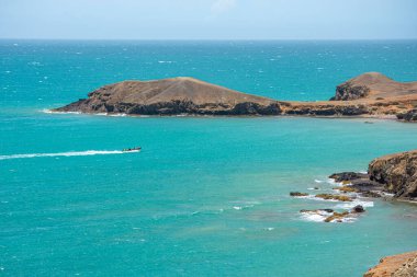 Cabo de la Vela, La Guajira, Kolombiya yakınlarında canlı turkuaz sularla çevrili bir kaya oluşumunun huzurlu bir görüntüsü..
