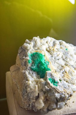 Zümrüt mineral yatağının yakın çekiminde doğal bir taş ayarı içinde canlı mavi-yeşil kristaller sergileniyor..