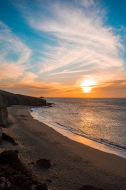 La Guajira, Kolombiya 'da sakin bir plajda gün batımı manzarası, canlı renkleri ve dingin dalgaları vurguluyor..