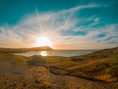 Kolombiya 'nın La Guajira sahilini aydınlatan çarpıcı bir günbatımı. Okyanus üzerinde canlı renkler ve dramatik bulutlarla..