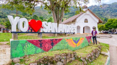 Tierradentro, Cauca, Kolombiya manzarasında geleneksel bir binanın yanında 'Yo San Andrs' yazılı canlı bir tabela yerel kültürü gözler önüne seriyor..