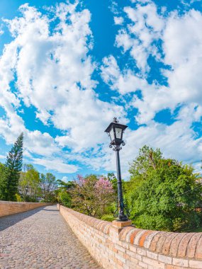 Popayn, Cauca, Kolombiya 'da yemyeşil ve mavi gökyüzü ile çevrili, bir lamba direğiyle süslenmiş bir kaldırım taşı köprüsünün pitoresk bir manzarası..