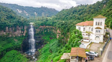 Yeşilliklerle çevrili Tequendama Şelaleleri 'nin çarpıcı manzarası ve yakınlarındaki tarihi bir bina. Bogot, Kolombiya 'nın büyüleyici doğal bir simgesi..