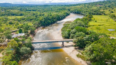 Putumayo, Kolombiya 'da bir nehir, bir köprü ve yemyeşil alan manzarası.
