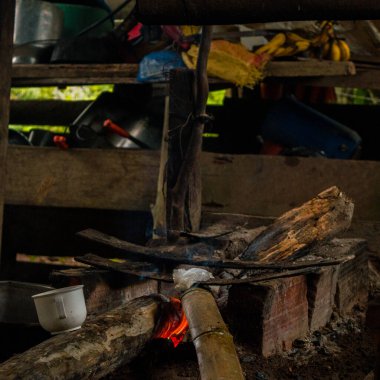 Arka planda bambu tüpü ve çatal bıçak bulunan ahşap bir pişirme alanında Kolombiya 'da geleneksel mutfak uygulamaları sergileniyor..