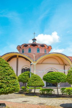 Putumayo, Kolombiya 'daki parlak mavi gökyüzünün altında canlı yeşilliklerle çevrili renkli bir kilisenin çarpıcı manzarası..