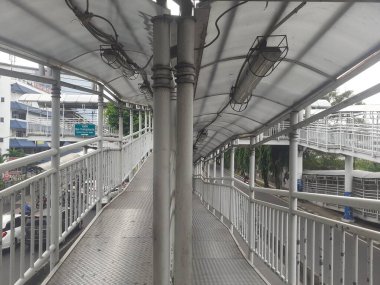 Jakarta, Endonezya, 30 Kasım 2022: Bir yaya köprüsünün mimari tasarım konsepti ve sabahleyin görülen Transjakarta otobüs yolcuları için bir otobüs durağı.