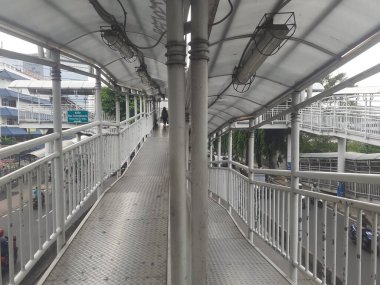 Jakarta, Endonezya, Kasım 28, 2022: Yaya geçidi köprüsü tasarımı ve sabah saatlerinde görülen Transjakarta otobüs yolcuları için otobüs durağı tasarımı.