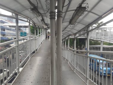 Jakarta, Endonezya, Kasım 28, 2022: Yaya geçidi köprüsü tasarımı ve sabah saatlerinde görülen Transjakarta otobüs yolcuları için otobüs durağı tasarımı.