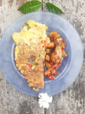 Kahvaltı spesiyali, doldurulmuş omlet menüsü, patates ve kızarmış tavuk tabakta. Ev yapımı. Ahşap arka plan..