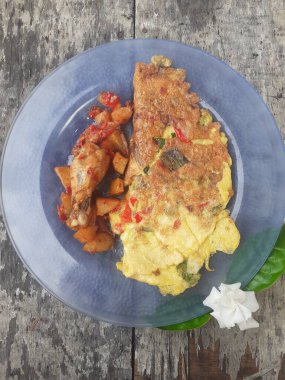 Kahvaltı spesiyali, doldurulmuş omlet menüsü, patates ve kızarmış tavuk tabakta. Ev yapımı. Ahşap arka plan..