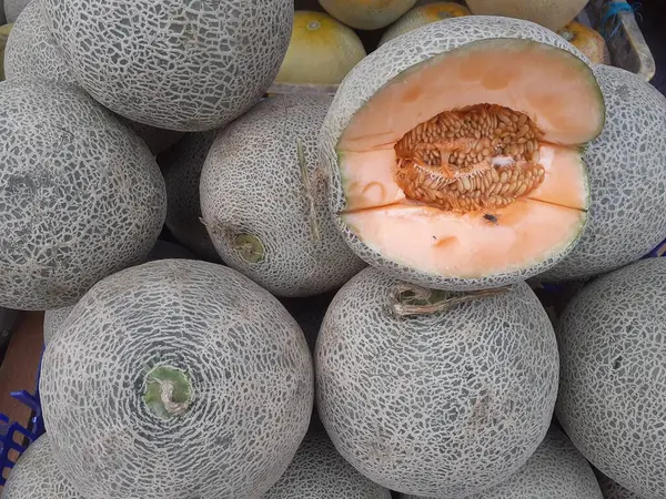 Cucumis melo, a melon, looks like a melon in half, which is cut by a traditional market fruit seller. Melons are included in the pumpkin family or Cucurbitaceae. They are high in Vitamin A and Vitamin C.