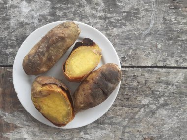 Küçük bir tabakta bal ile kızartılmış Cilembu tatlı patatesi. Ahşap masa arka planı. Cilembu tatlı patatesi, Cilembu köyünde yetişen yerel bir patates yetiştiricisidir..