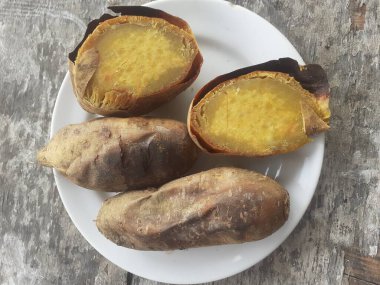 Küçük bir tabakta bal ile kızartılmış Cilembu tatlı patatesi. Ahşap masa arka planı. Cilembu tatlı patatesi, Cilembu köyünde yetişen yerel bir patates yetiştiricisidir..