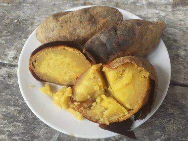 Küçük bir tabakta bal ile kızartılmış Cilembu tatlı patatesi. Ahşap masa arka planı. Cilembu tatlı patatesi, Cilembu köyünde yetişen yerel bir patates yetiştiricisidir..