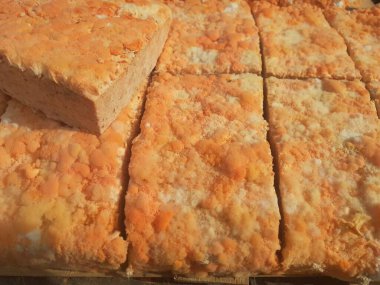 Geleneksel bir yol kenarı pazarında ahşap bir rafta çiğ oncom. Oncom, yer fıstığı keki ve tofu dreglerinden yapılan mantar ezmeli bir tempeh. Oncom, çeşitli küf türleri olan mayalanmış bir yemektir..