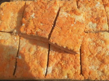 Geleneksel bir yol kenarı pazarında ahşap bir rafta çiğ oncom. Oncom, yer fıstığı keki ve tofu dreglerinden yapılan mantar ezmeli bir tempeh. Oncom, çeşitli küf türleri olan mayalanmış bir yemektir..