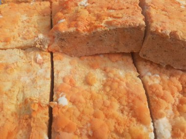 Geleneksel bir yol kenarı pazarında ahşap bir rafta çiğ oncom. Oncom, yer fıstığı keki ve tofu dreglerinden yapılan mantar ezmeli bir tempeh. Oncom, çeşitli küf türleri olan mayalanmış bir yemektir..