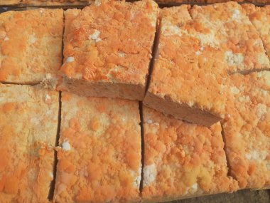 Geleneksel bir yol kenarı pazarında ahşap bir rafta çiğ oncom. Oncom, yer fıstığı keki ve tofu dreglerinden yapılan mantar ezmeli bir tempeh. Oncom, çeşitli küf türleri olan mayalanmış bir yemektir..