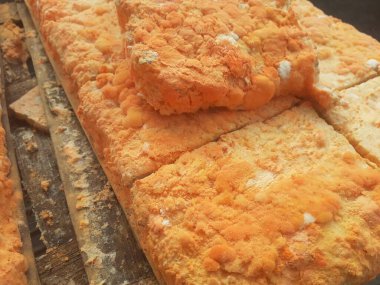 Geleneksel bir yol kenarı pazarında ahşap bir rafta çiğ oncom. Oncom, yer fıstığı keki ve tofu dreglerinden yapılan mantar ezmeli bir tempeh. Oncom, çeşitli küf türleri olan mayalanmış bir yemektir..