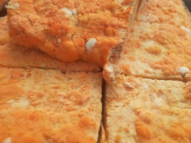 Geleneksel bir yol kenarı pazarında ahşap bir rafta çiğ oncom. Oncom, yer fıstığı keki ve tofu dreglerinden yapılan mantar ezmeli bir tempeh. Oncom, çeşitli küf türleri olan mayalanmış bir yemektir..