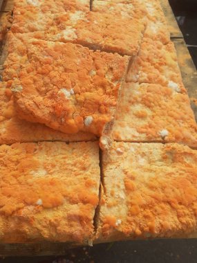 Geleneksel bir yol kenarı pazarında ahşap bir rafta çiğ oncom. Oncom, yer fıstığı keki ve tofu dreglerinden yapılan mantar ezmeli bir tempeh. Oncom, çeşitli küf türleri olan mayalanmış bir yemektir..