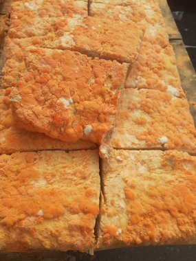 Geleneksel bir yol kenarı pazarında ahşap bir rafta çiğ oncom. Oncom, yer fıstığı keki ve tofu dreglerinden yapılan mantar ezmeli bir tempeh. Oncom, çeşitli küf türleri olan mayalanmış bir yemektir..