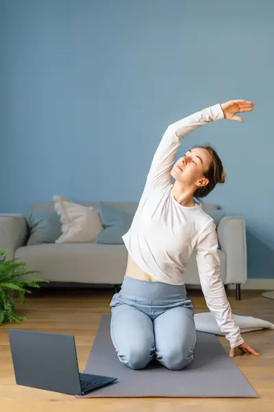 Woman is doing yoga at home in the living room. Concept of a healthy lifestyle and active recreation.