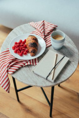Kahvaltı için çikolatalı kruvasan ve ahududu ile bir fincan kahve..