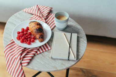 Kahvaltı için çikolatalı kruvasan ve ahududu ile bir fincan kahve..