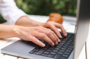 Bir kafedeki iş toplantısında tanınmayan kadın elleri dizüstü bilgisayarda klavyeyle yazı yazıyor..